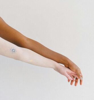 Two arms of different skin tones displayed on a white background, one with a tattoo.