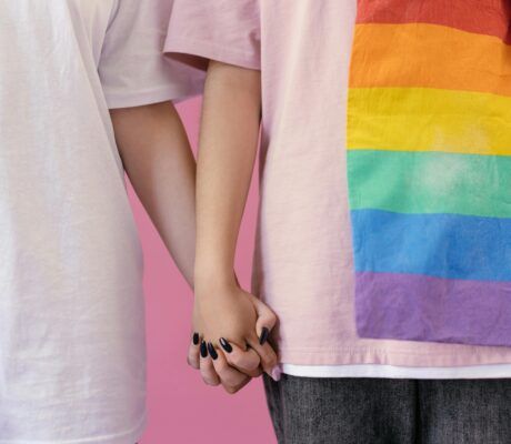 Close-up of two people holding hands, symbolizing love and LGBTQ+ pride.