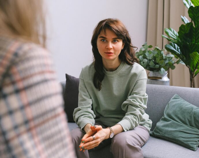 A focused woman during a therapy session, seated on a sofa indoors.