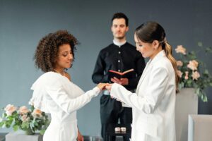 A joyful LGBTQ+ couple exchanging rings during their wedding ceremony, officiated with elegance.